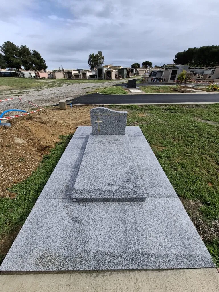 Sépulture sobre et moderne en granit gris clair posée dans un cimetière paysager