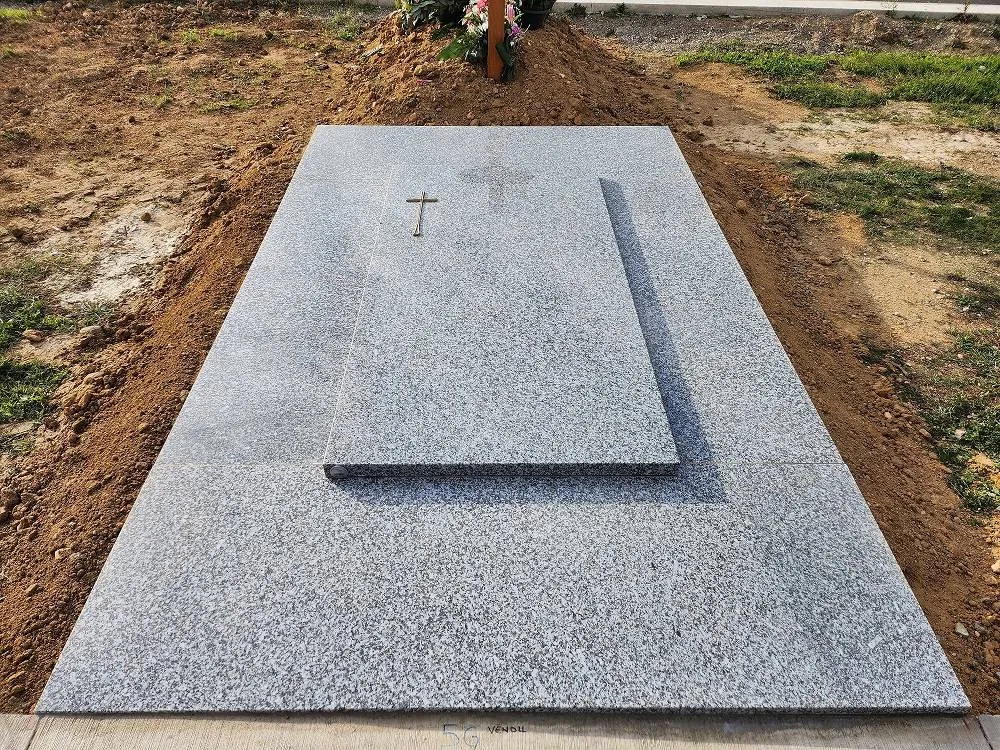 Sépulture en granit gris clair avec gravure d'une croix sobre sur la pierre tombale