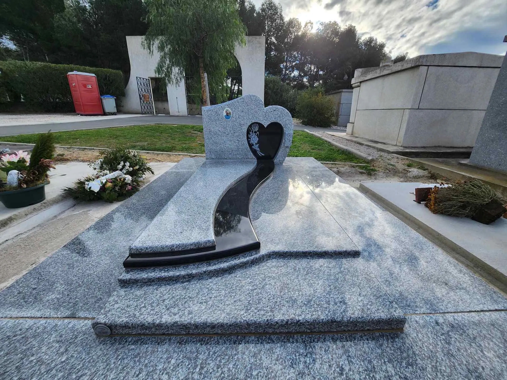 Pierre tombale moderne en granit gris avec stèle en cœur et motif de vague noire